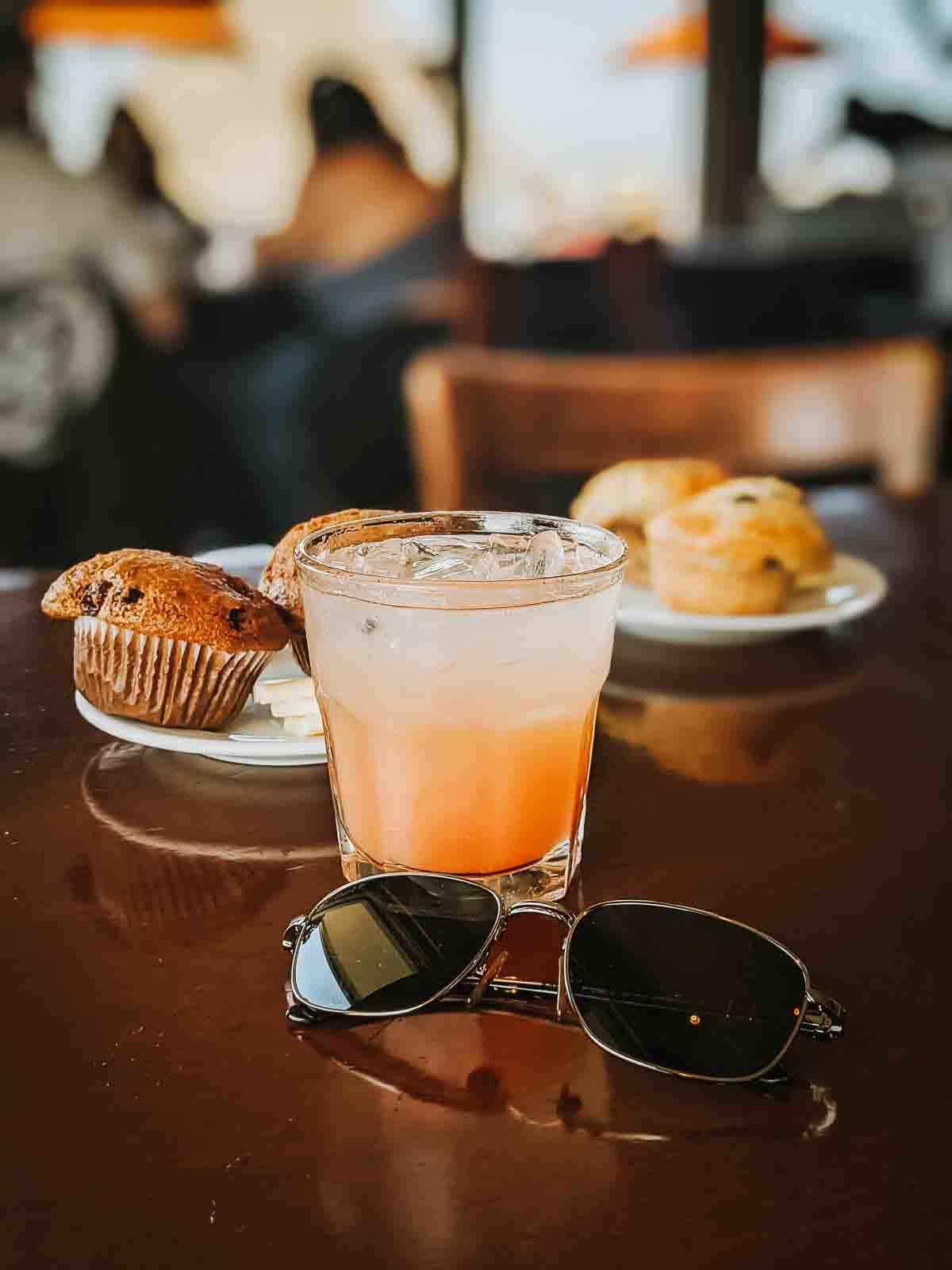 Brunch drink, muffins and sunglasses on a table. 
