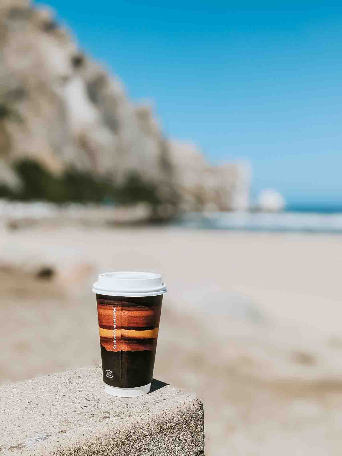 Coffee cup with Morro Rock blurred in background. 
