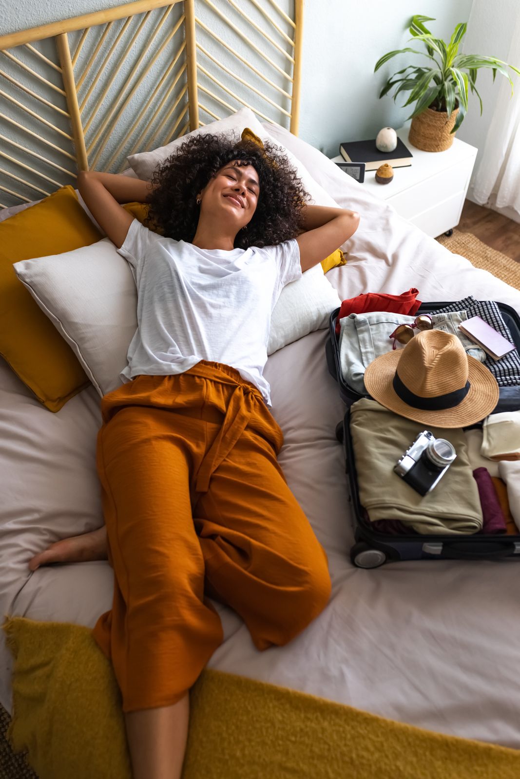 Woman laying on bed unpacking at a hotel. 
