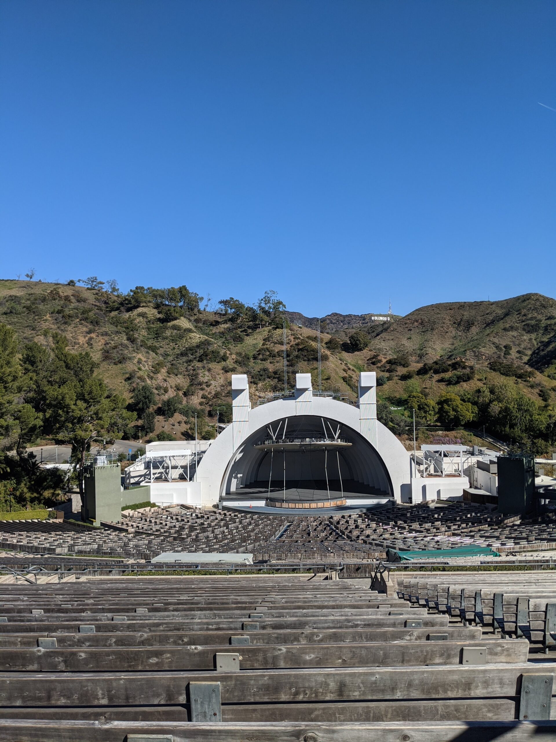 View of the Hollywood Bowl at the top of the seating area with distant iconic Hollywood sign in the peaks above.
