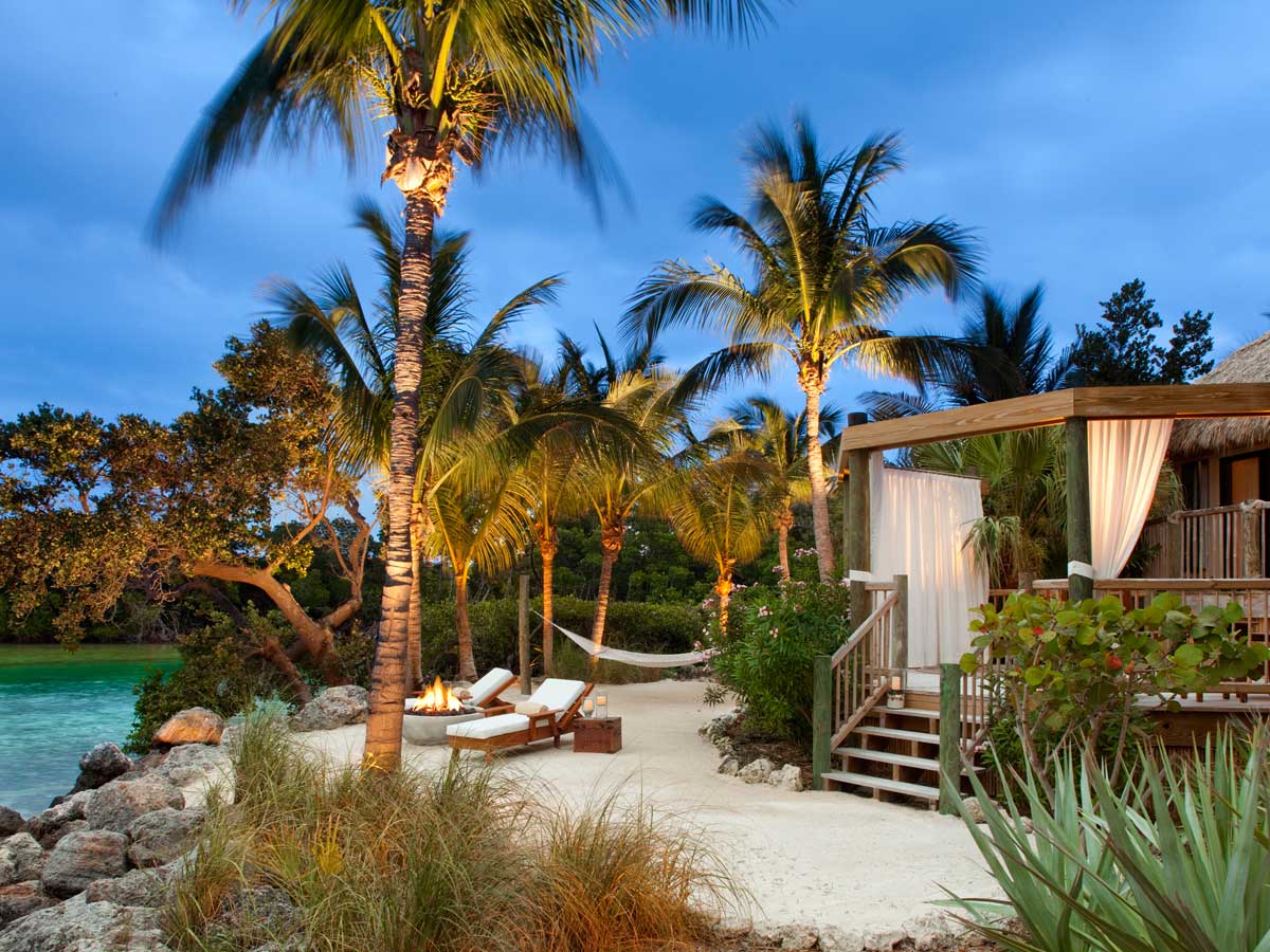 Little Palm Island Resort & Spa exterior on the beach with hammock and palm trees at night,