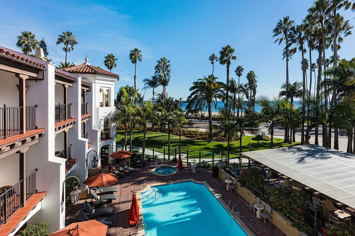 View of the pool, palm trees, and beach at Santa Barbara Inn.