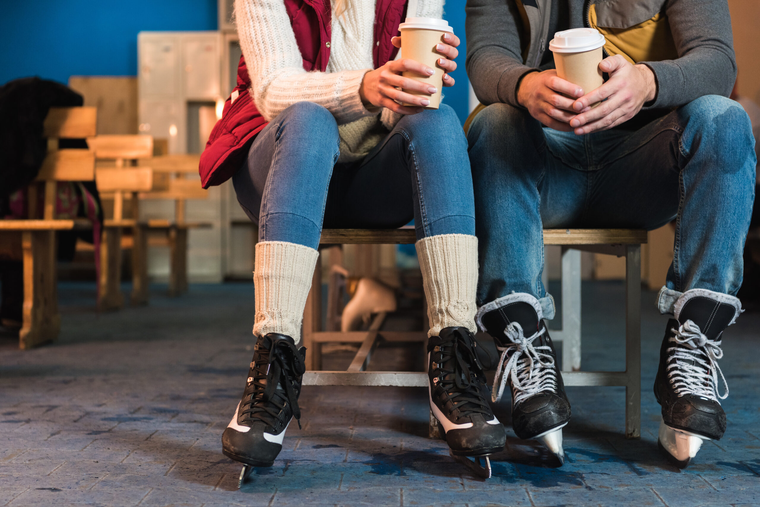 A couple sitting with ice skates on and holding hot beverages, one of the most romantic and fun Northern California date ideas.