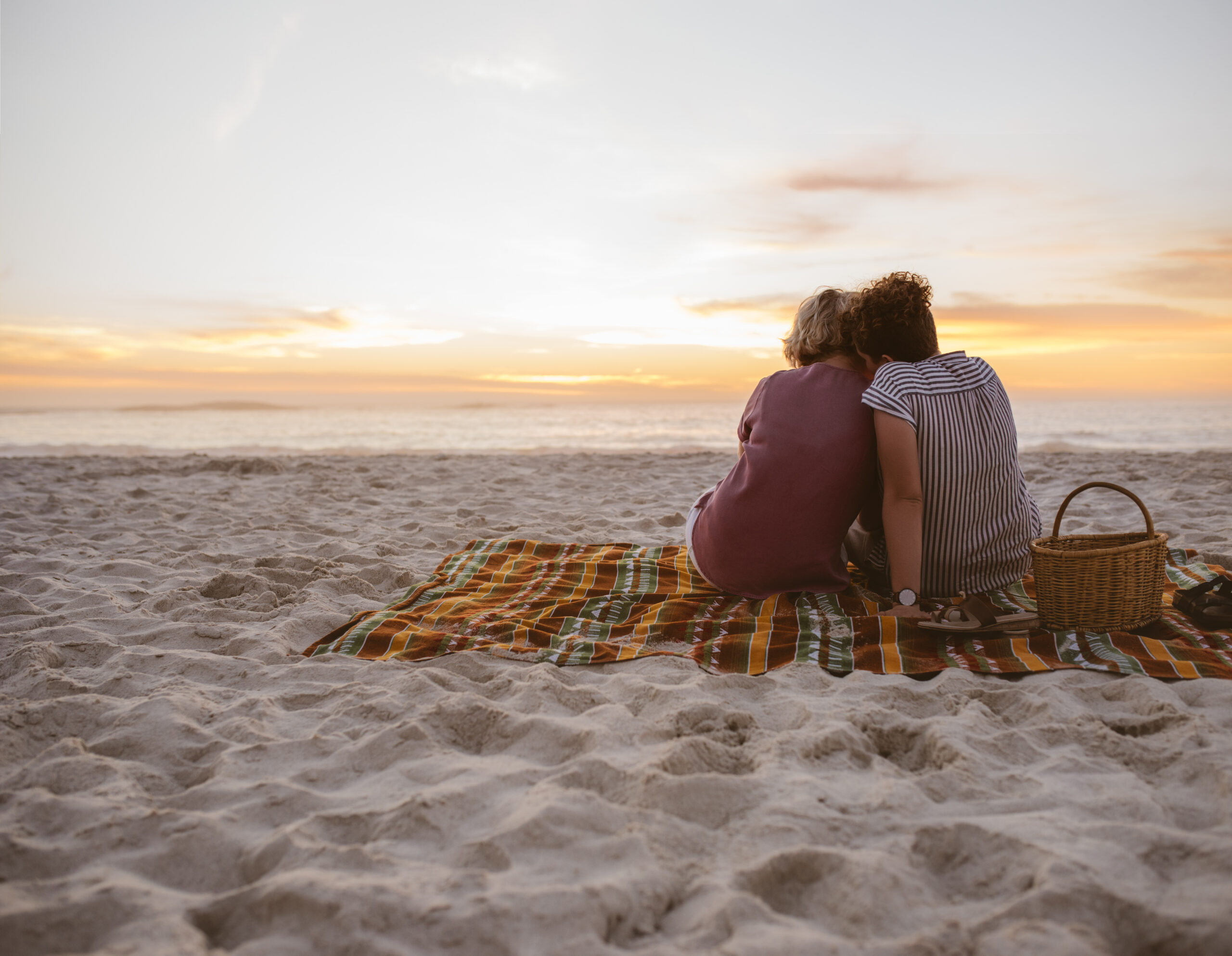 Same sex couple having a picnic on the beach at sunset on the Florida Gulf Coast.