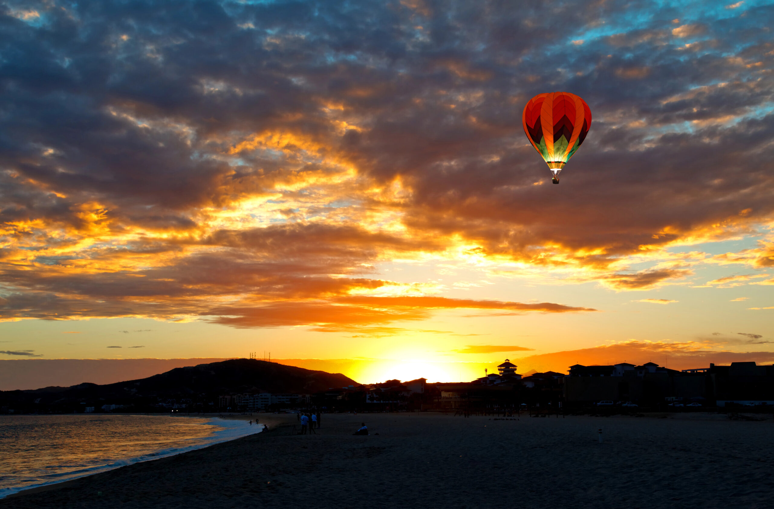 Hot air balloon at sunset over the beach.