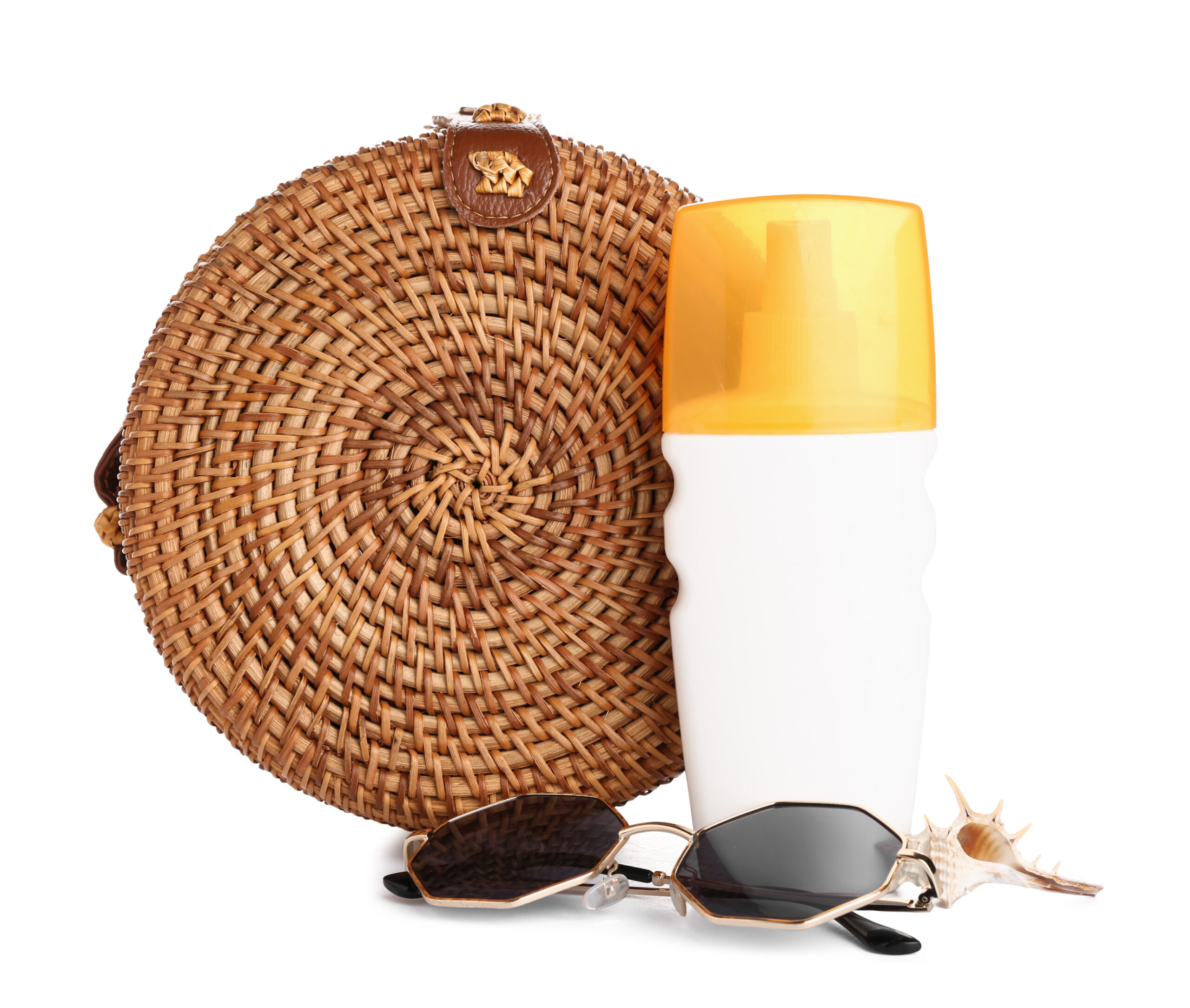 Wicker bag with sunglasses, bottles of sunscreen cream and seashell isolated on white background for Beach side hotel getaway. 