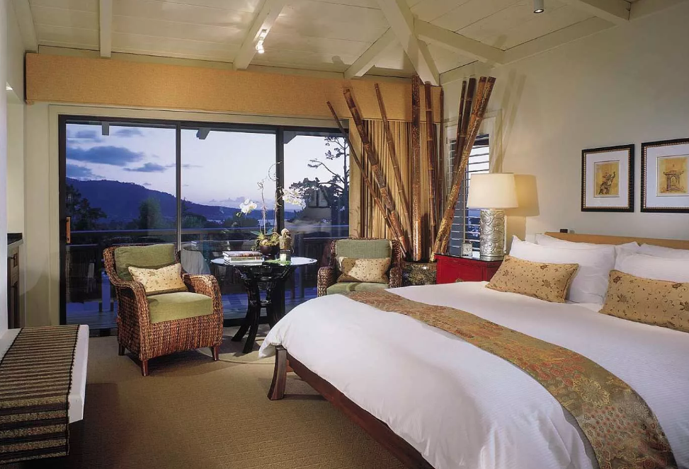 Golden Asian-themed room with big windows overlooking mountains at dusk.