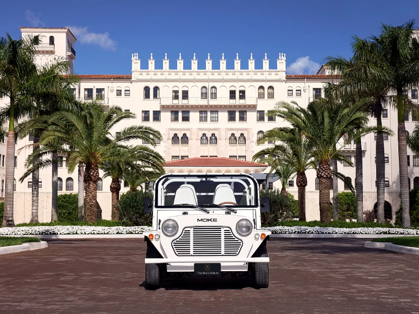 Exterior view of the Boca Raton with palm trees and a white jeep.