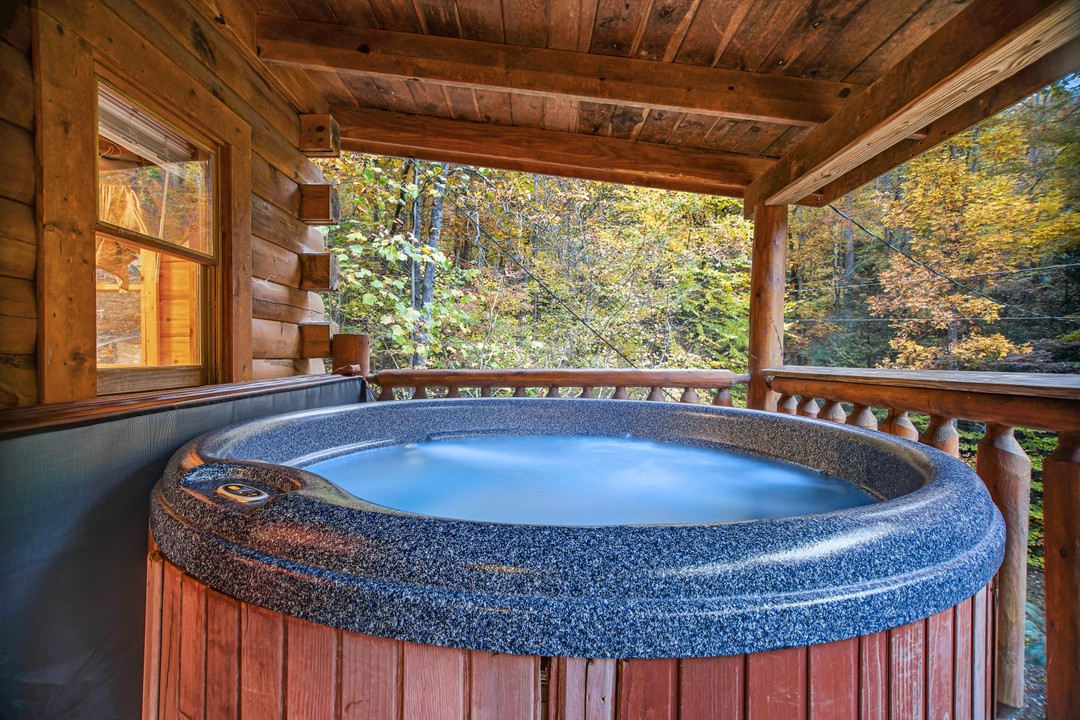 Hot tub on deck of cabin in the woods.