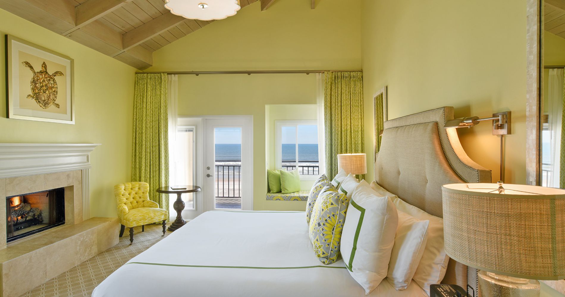 Oceanfront king bed suite with yellow-green walls and furniture. 