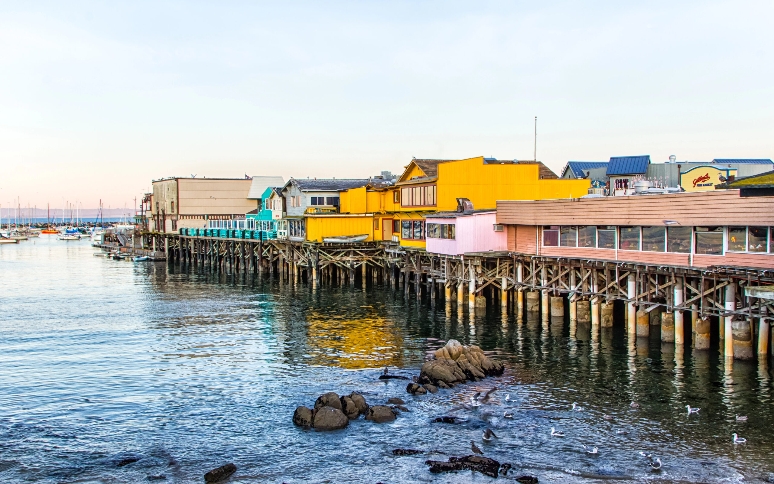 Monterey Bay pier with colorful buildings at golden hour. 