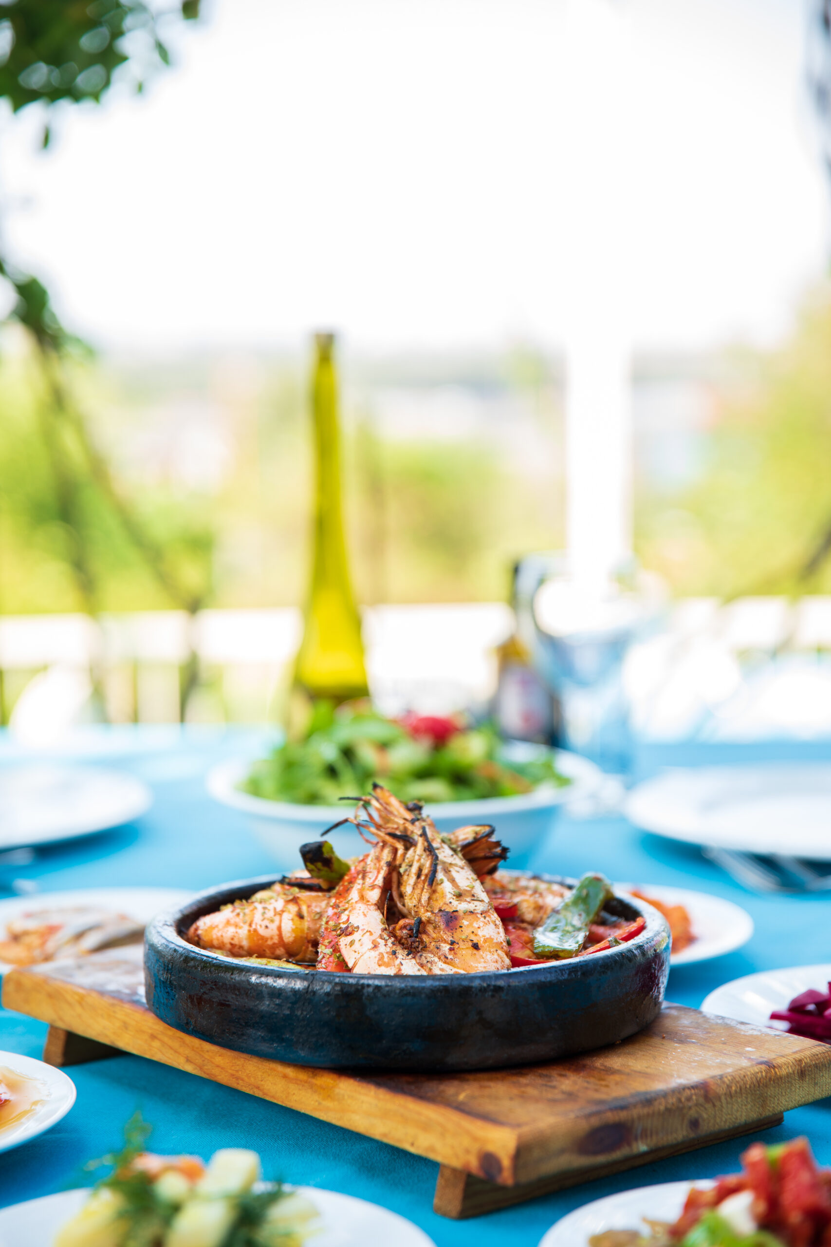 A black bowl of shrimp on a bright turquoise tablecloth.