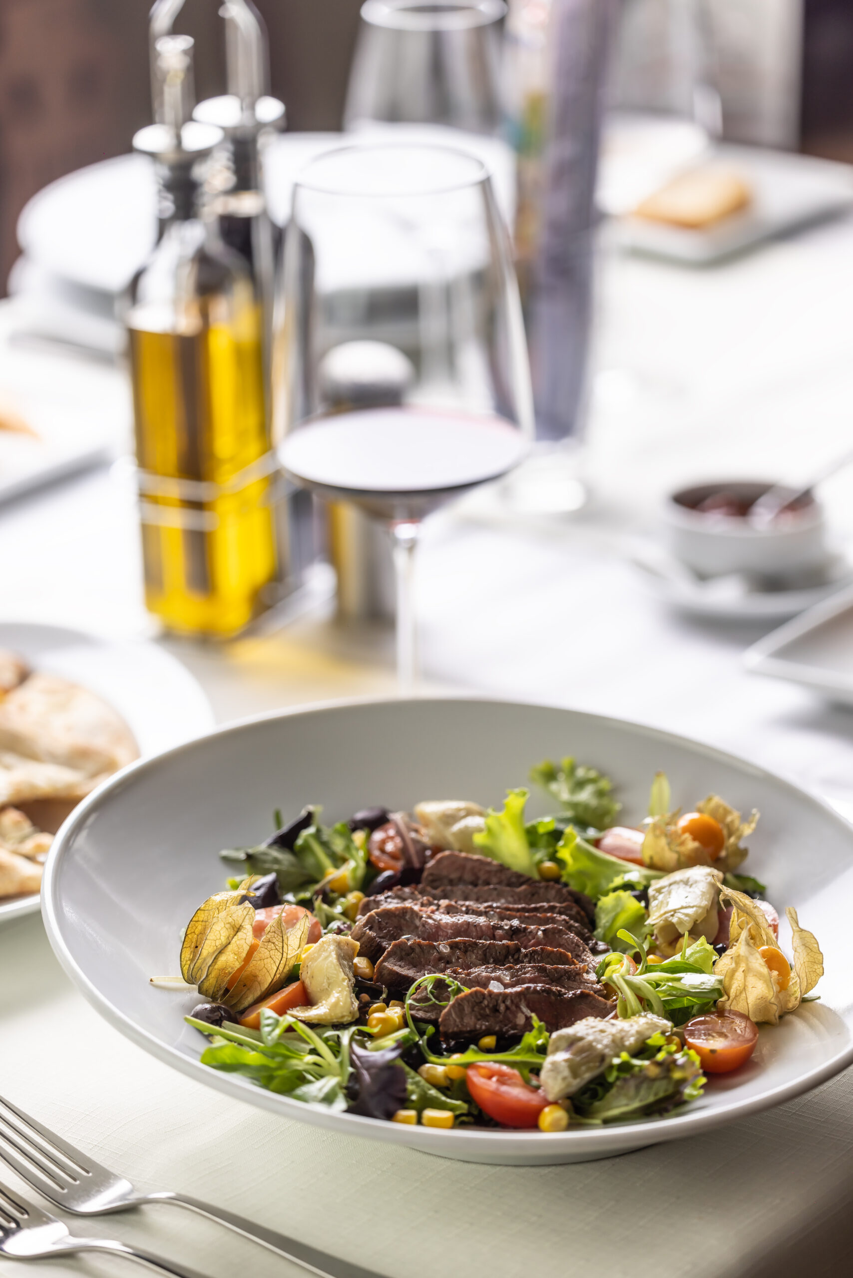 Set table with steak and salad with condiments next to it in a restaurant.