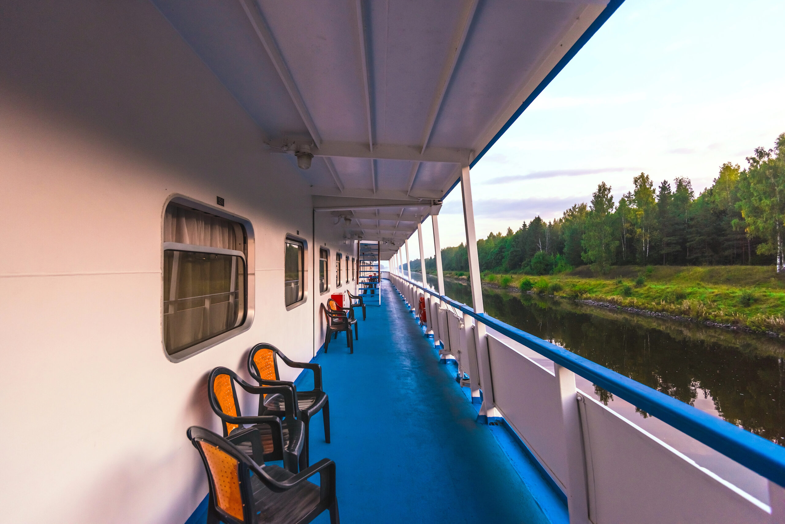 View from deck of river cruise boat with chairs and greenery.