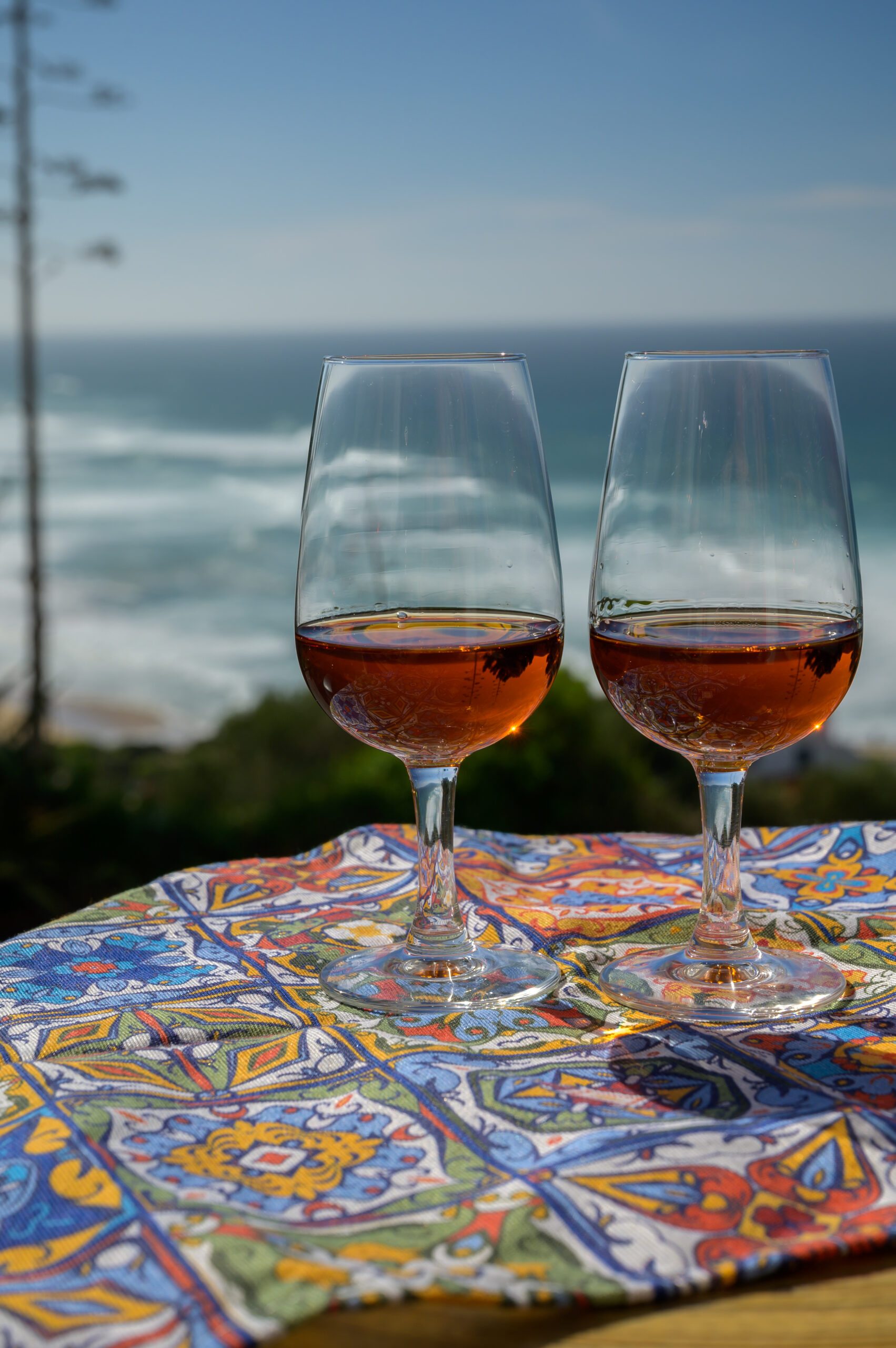 Tasting of sweet moscatel de setubal or porto portuguese wine and view on sunny blue Atlantic ocean near Sintra in Lisbon area, Portugal.