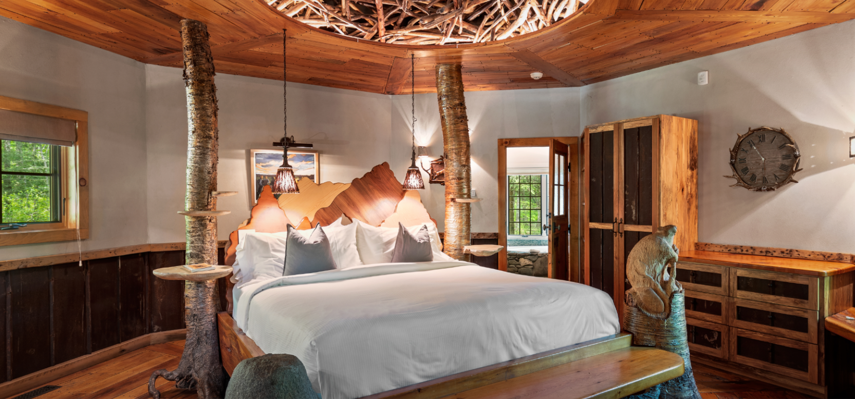 King bed with white linen sheets with tree trunks accenting the room for a natural feel - a secluded romantic getaways in the USA.