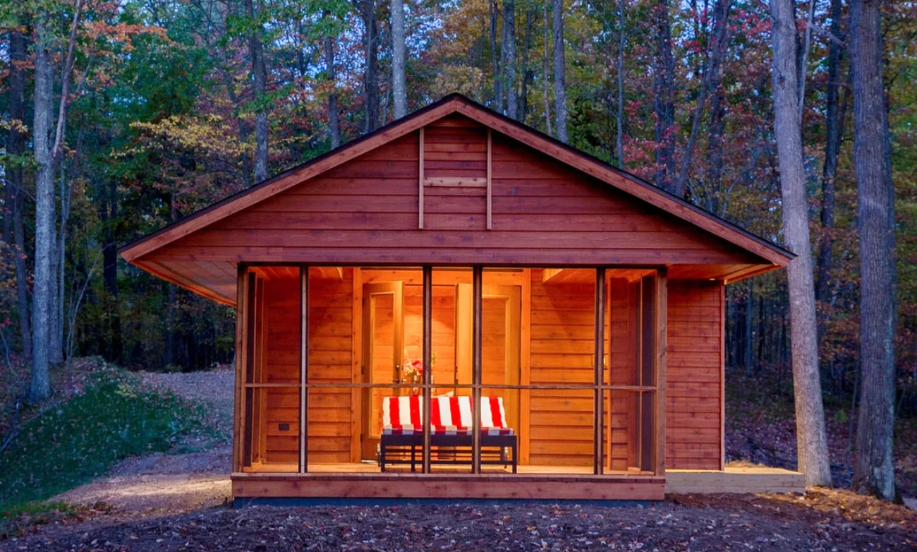 A secluded wooden cabin in the woods at dusk with fall foliage, a secluded romantic getaways in the USA.