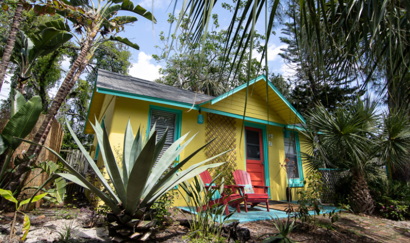 A yellow cottage with turquoise trimming at firefly cottage surrounded by lunch palms. It's one of the most secluded romantic getaways in the USA!