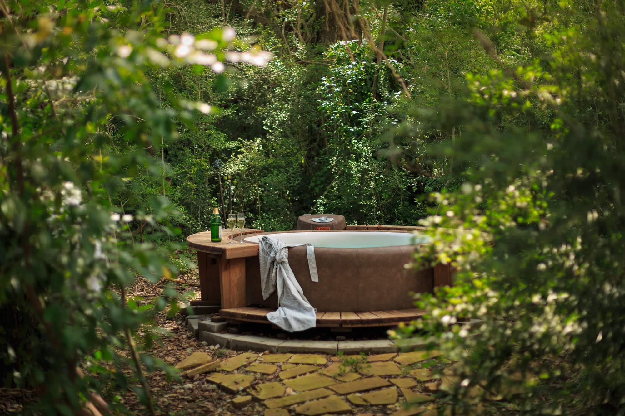 A secluded hot tub in a lush green forest with bubbles and a towel, a secluded romantic getaways in the USA.