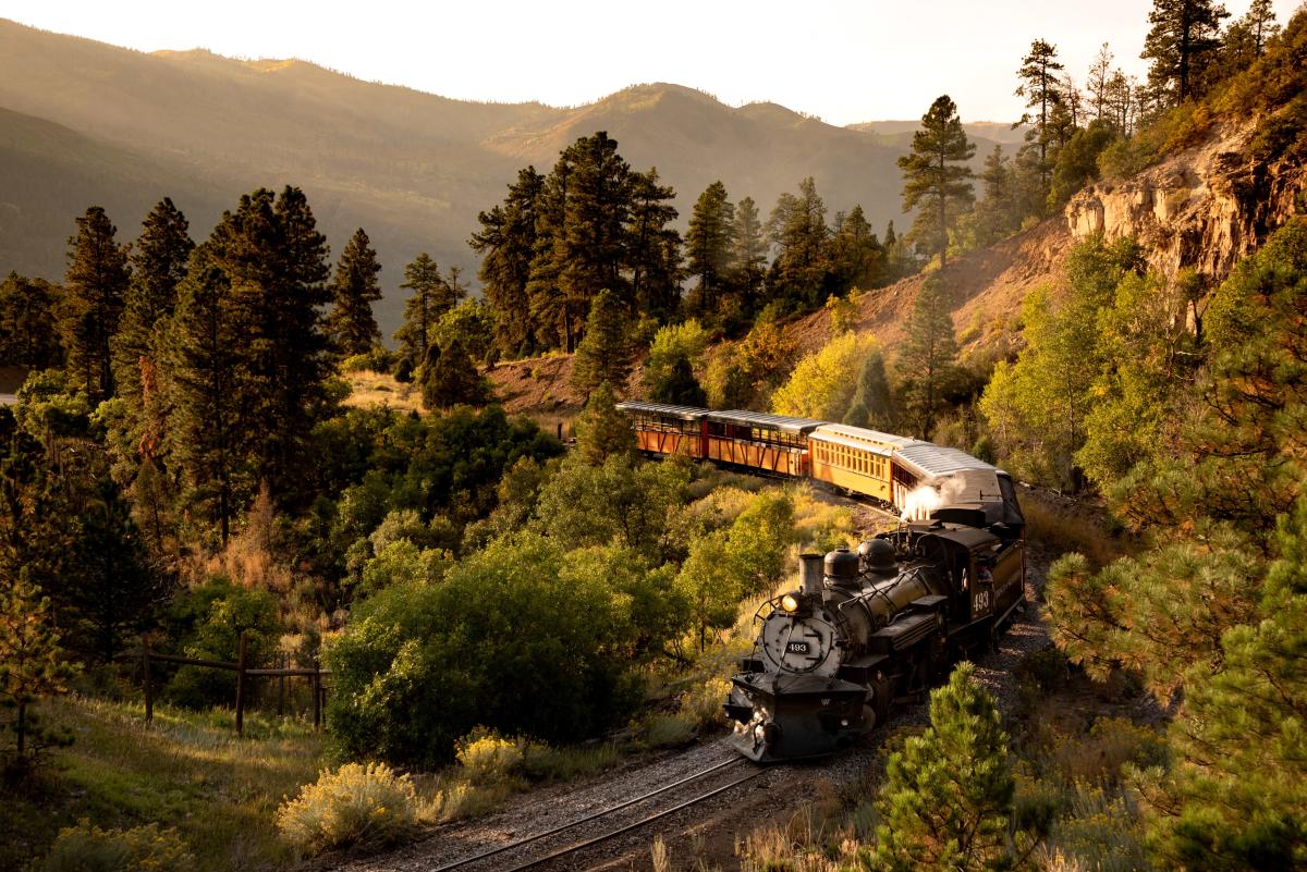 Durango train going around the bend in fall colors at golden hour, one of the most romantic getaways in the Fall.