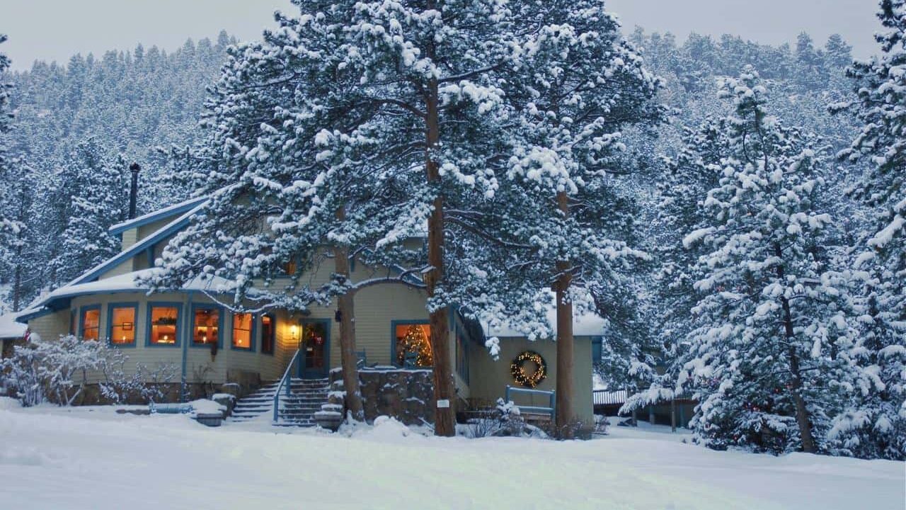 Exterior of The Romantic Riversong Inn surrounded by snow covered trees, one of the most romantic getaways in November. 