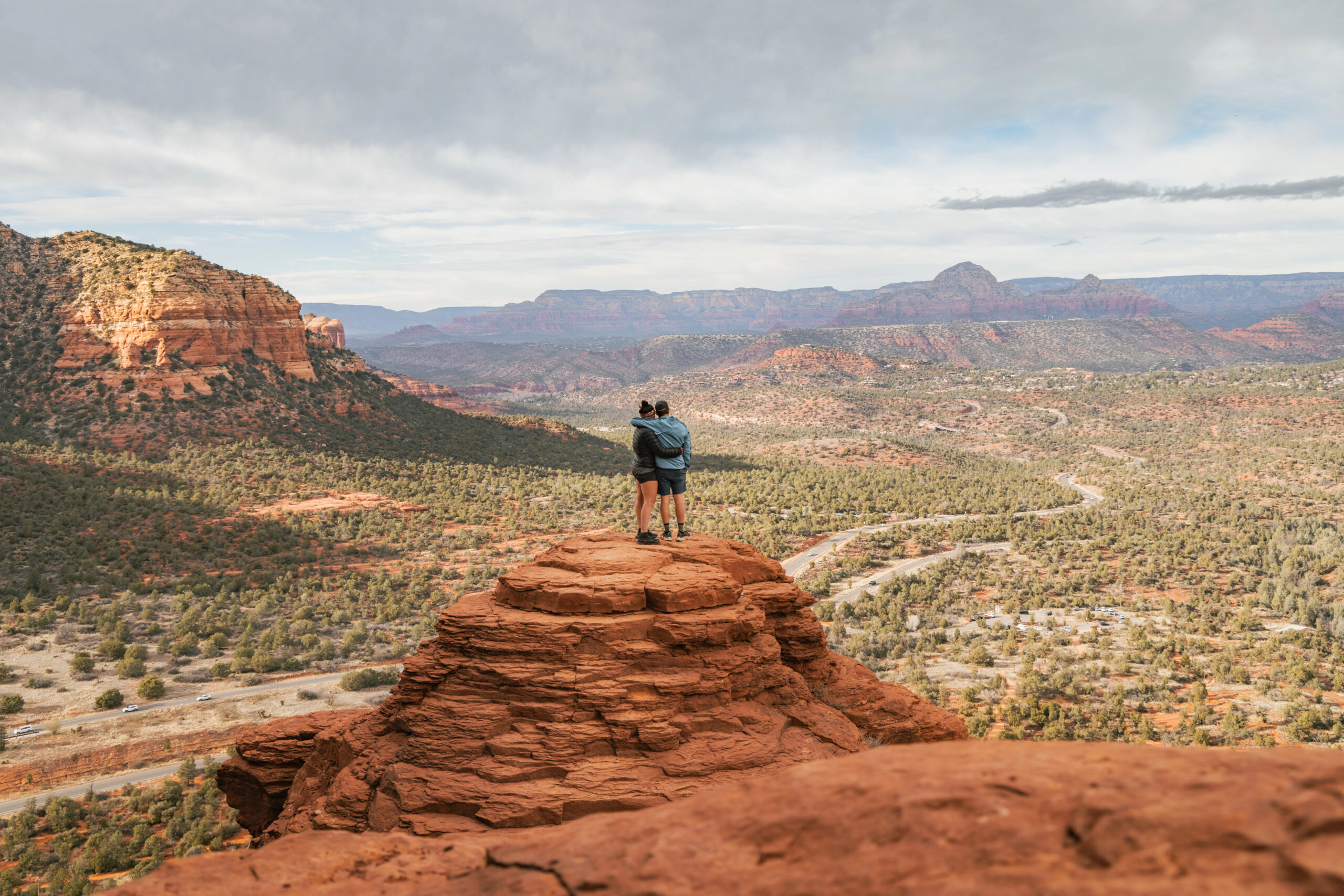 Couple hugging on a cliff enjoying their romantic weekend in Sedona.