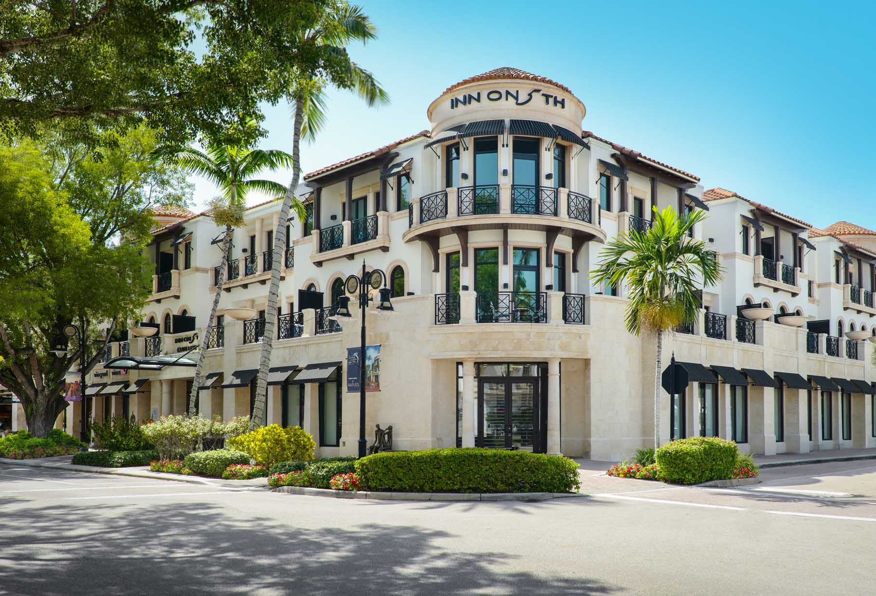 Exterior shot of Inn on Fifth in the bright sunshine with palm trees. It's one of the best hotels in Naples, Florida.