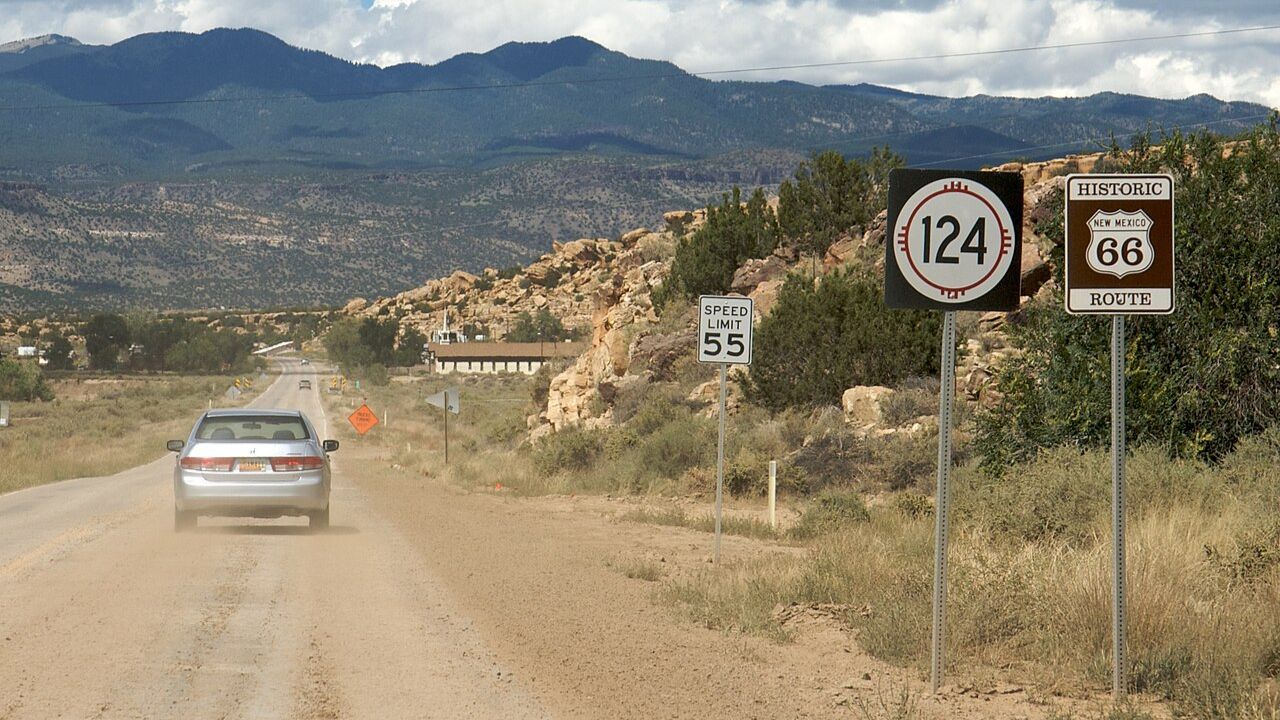 A car drives along Historic Route 66 through New Mexico’s desert landscape