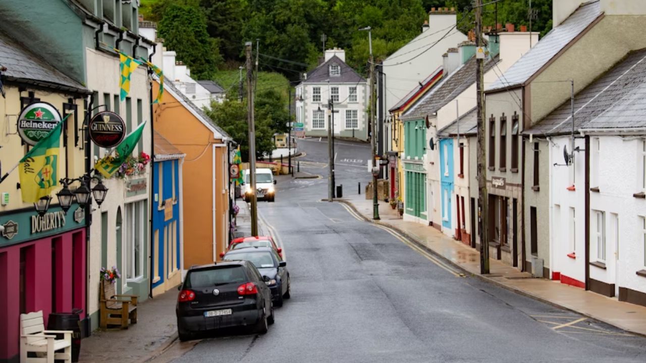 Colorful buildings and pubs line a quiet, wet village street.
