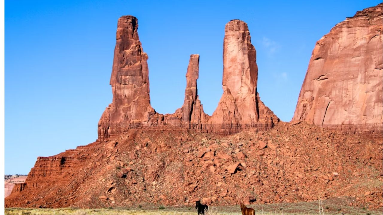 Monument Valley’s iconic sandstone formations in Arizona, with two horses in the foreground.