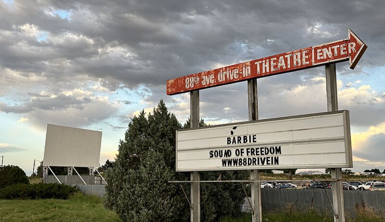 Vintage entrance sign for 88 Drive-In Theatre in Commerce City, Colorado, displaying current films Barbie and Sound of Freedom with cloudy skies in the background.