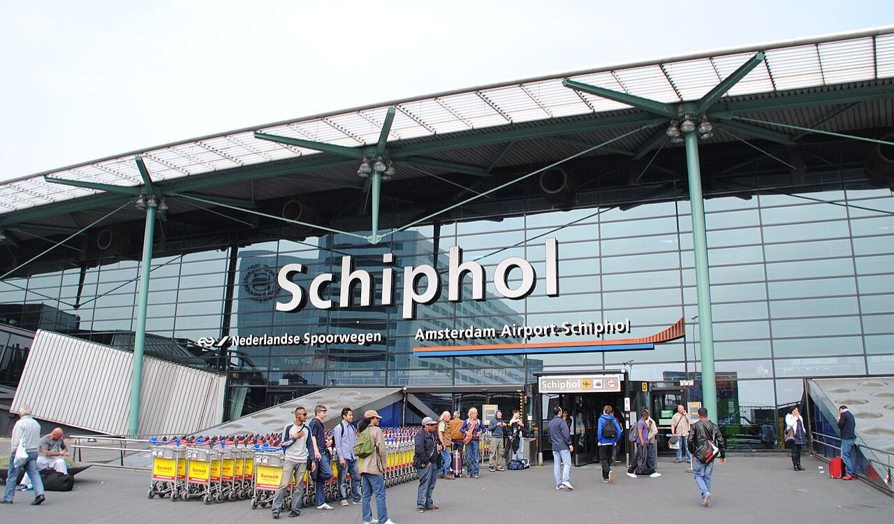Exterior of Amsterdam Schiphol Airport (AMS) with passengers and signage