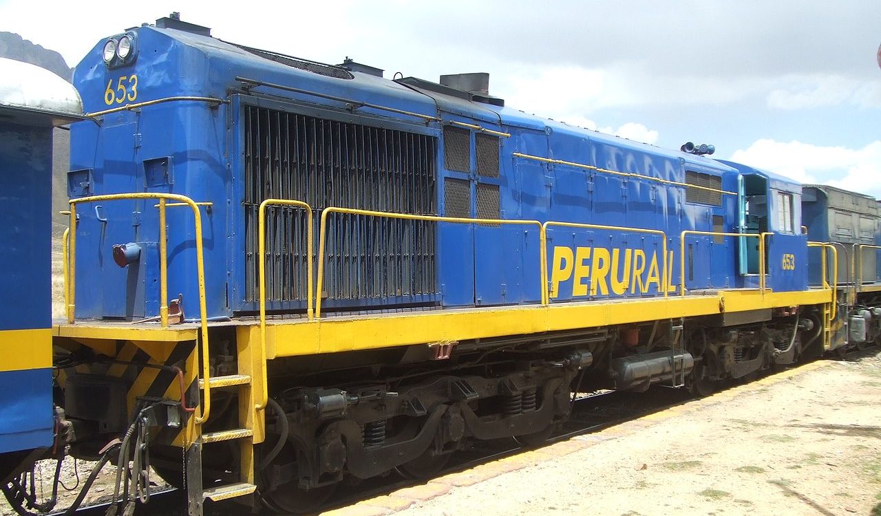 Bright blue and yellow PeruRail train at a station in the Andes