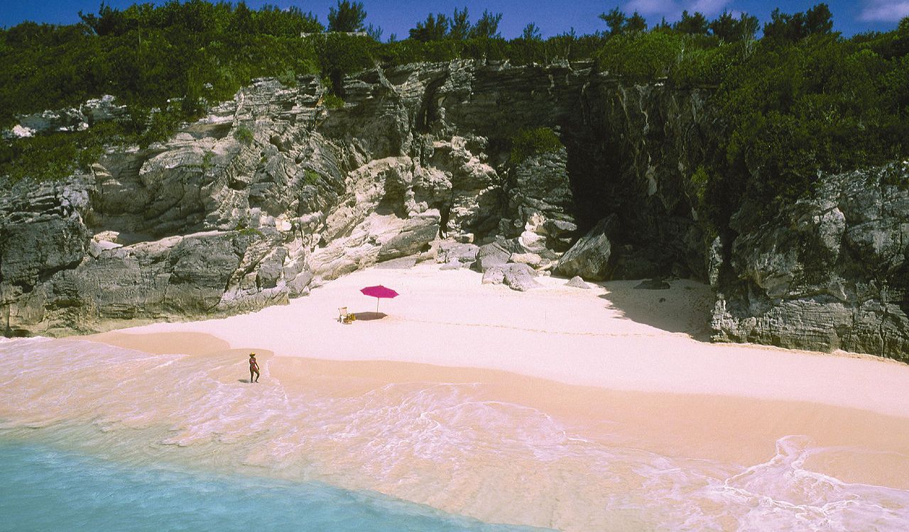 Secluded pink sands beneath rocky cliffs