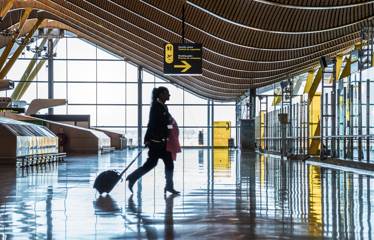 Traveler walking through modern Burlington Airport terminal with suitcase.