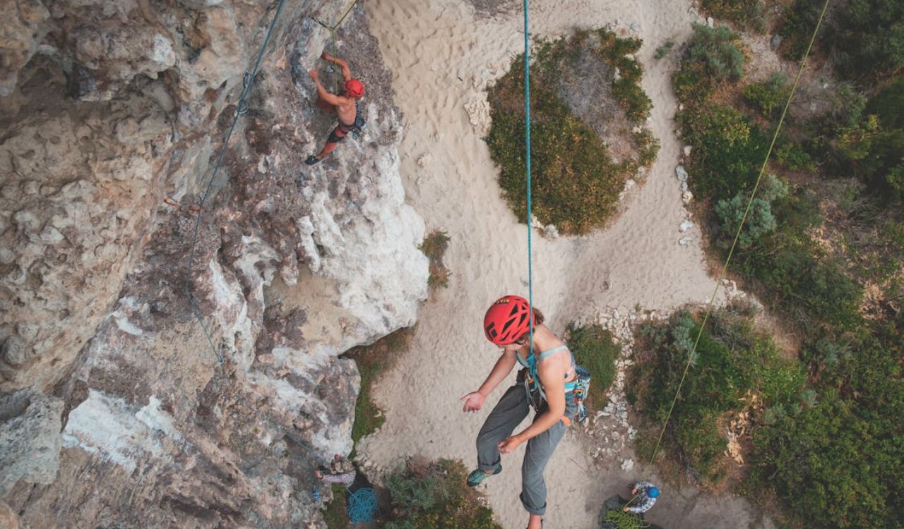 Solo traveler rock climbing with safety gear, highlighting the importance of travel insurance
