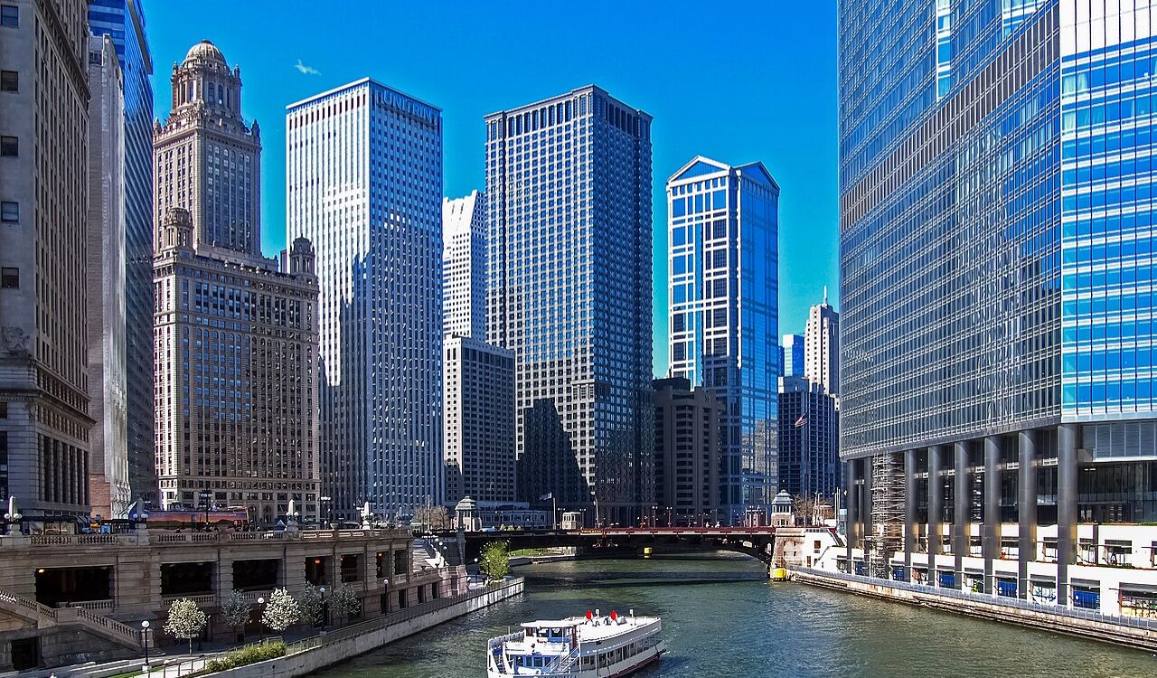 Boat cruising along the Chicago River surrounded by tall modern skyscrapers