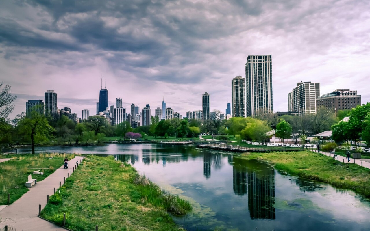Chicago skyline with park and lake reflection.