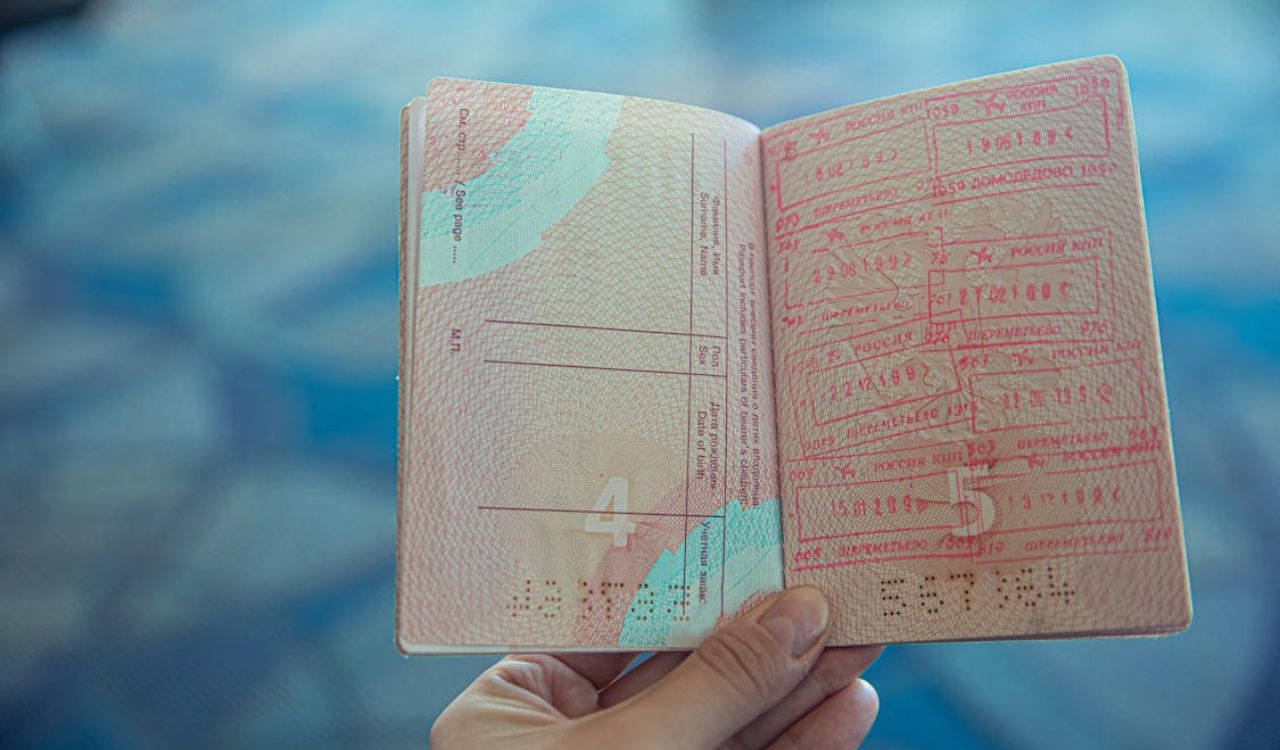 Close-up of a hand holding an open passport with multiple visa stamps