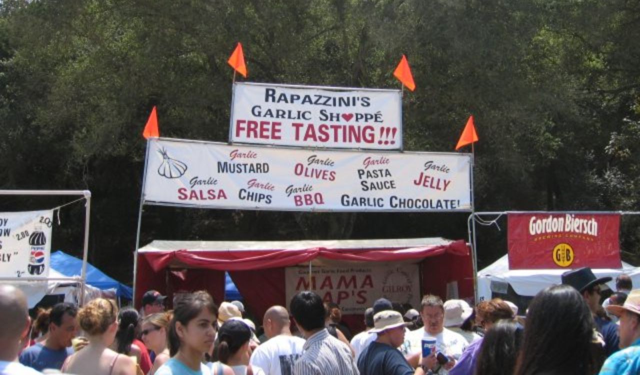Crowd at Gilroy Garlic Festival near a tasting booth with garlic-themed foods