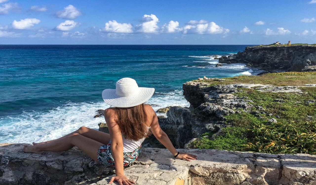 A Woman in White Hat Sitting on the Beach