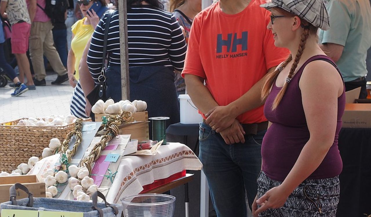 A man and woman chat near a stall selling garlic braids at the Isle of Wight Garlic Festival in the UK