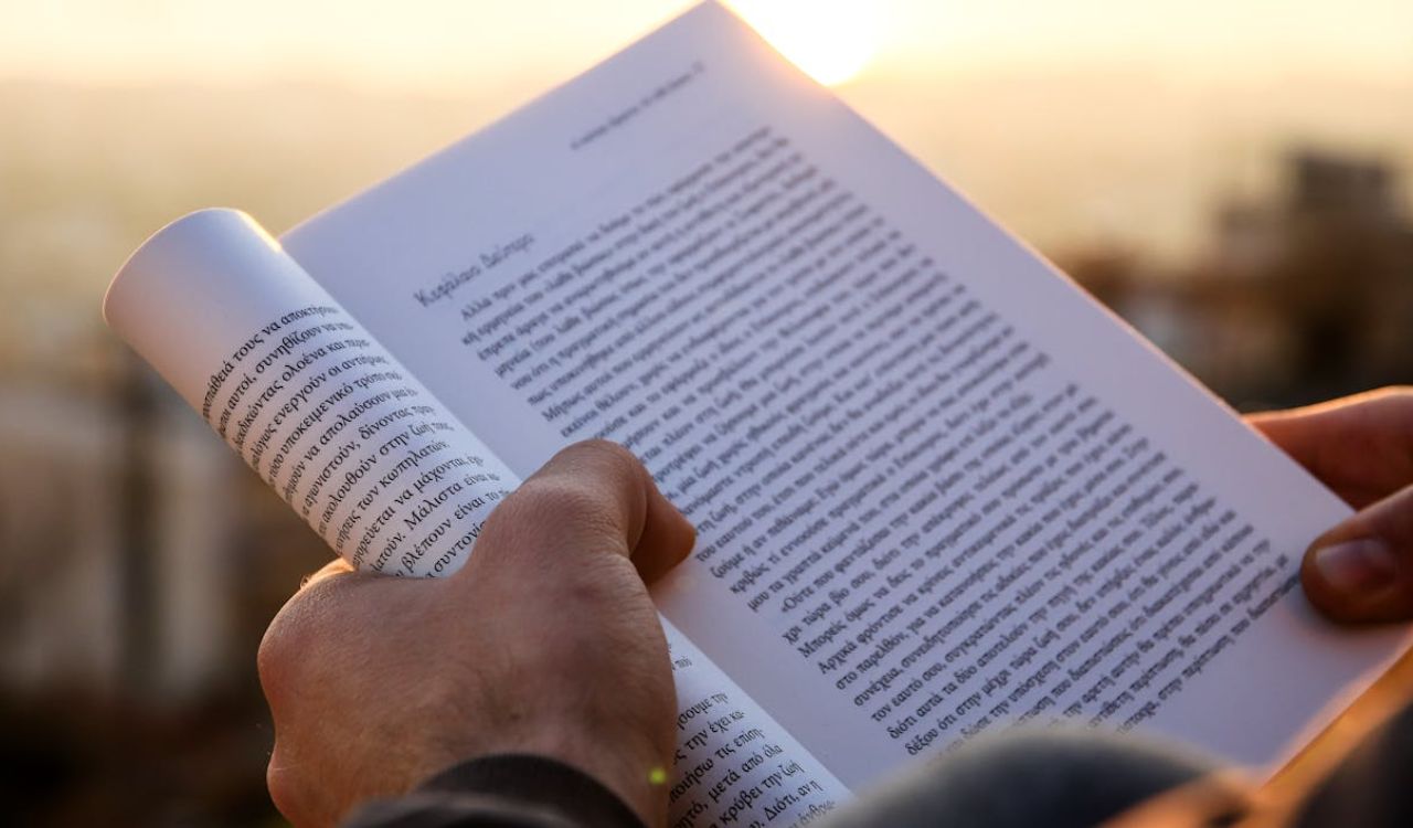 Close-up of hands holding and reading a book in a foreign language, symbolizing learning basics before travel.