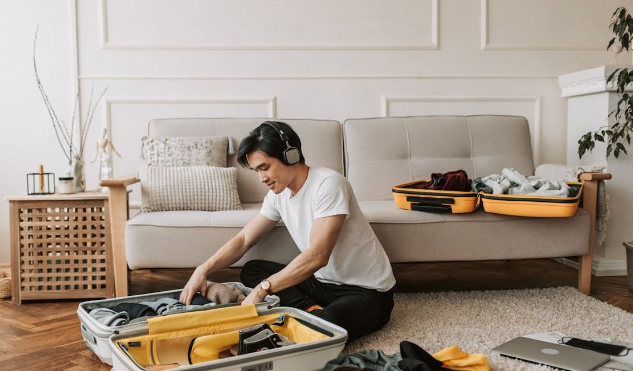 Man packing a suitcase in a living room, preparing travel essentials as part of a backup plan