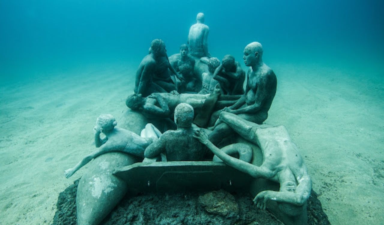 Underwater statues of people in a raft at Museo Atlántico, Lanzarote