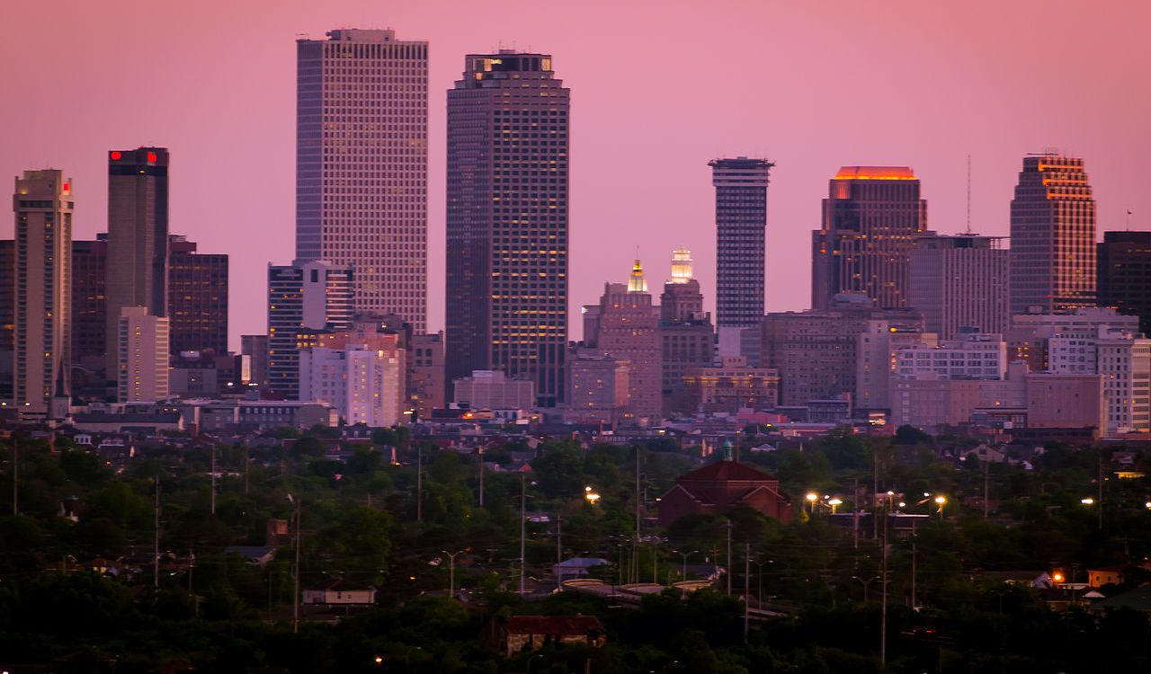 Skyline of New Orleans, Louisiana at sunset with tall buildings glowing in the evening light