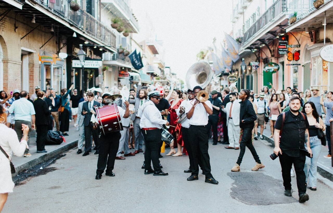 A street band performs for a crowd on a busy city street lined with historic buildings and balconies.