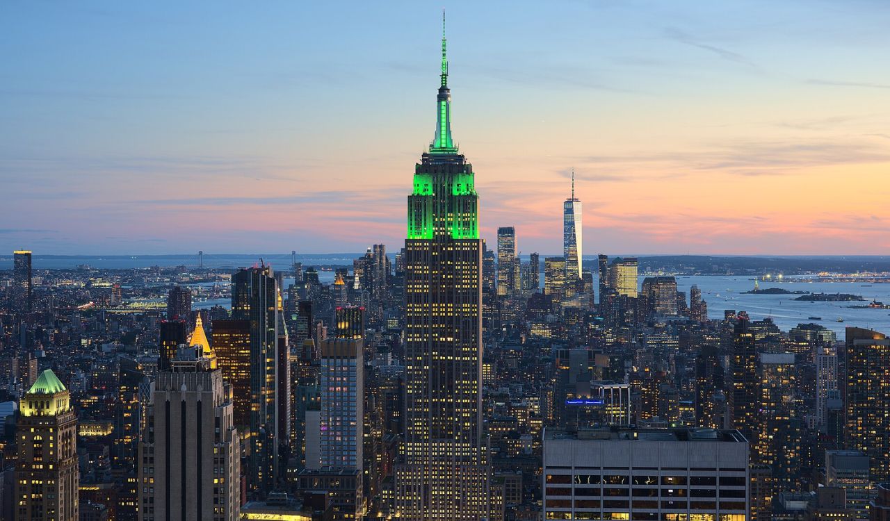 Empire State Building glowing green at dusk in the New York City skyline