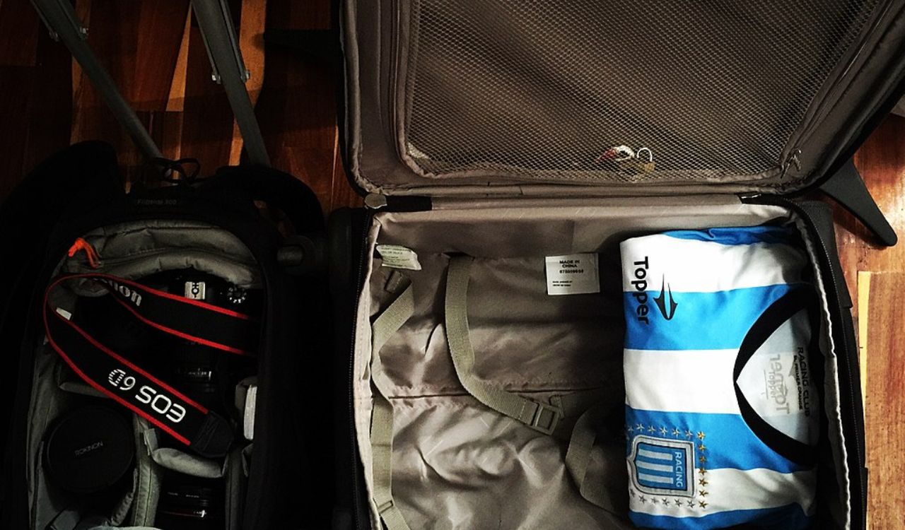 Open suitcase with a folded shirt and camera gear, showing light and smart packing for travel