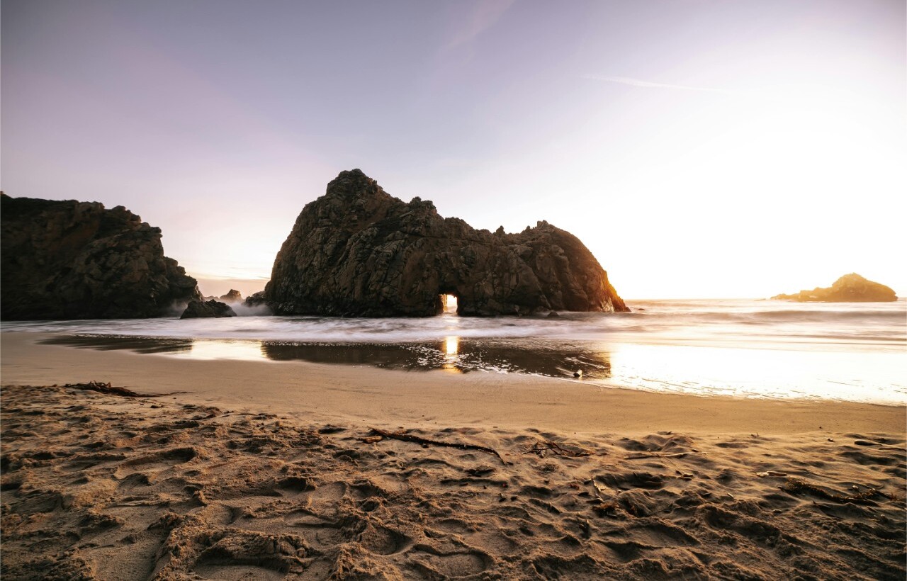 Sunset through rock arch at Pfeiffer Beach, Big Sur